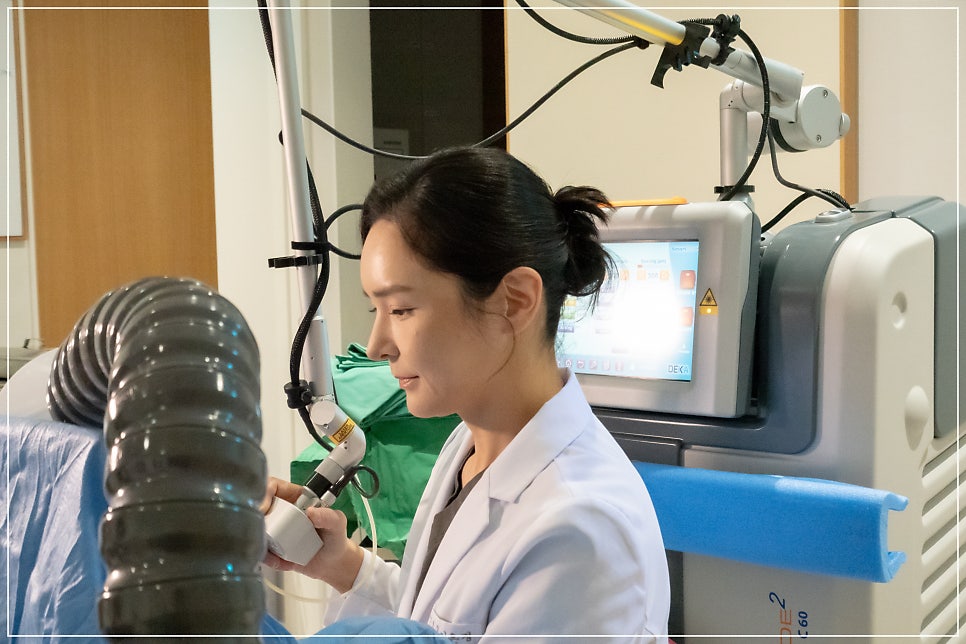 흰 가운의 의료진이 대형 레이저/시술 장비(모니터 화면·호스 부착)를 조작하는 옆모습
