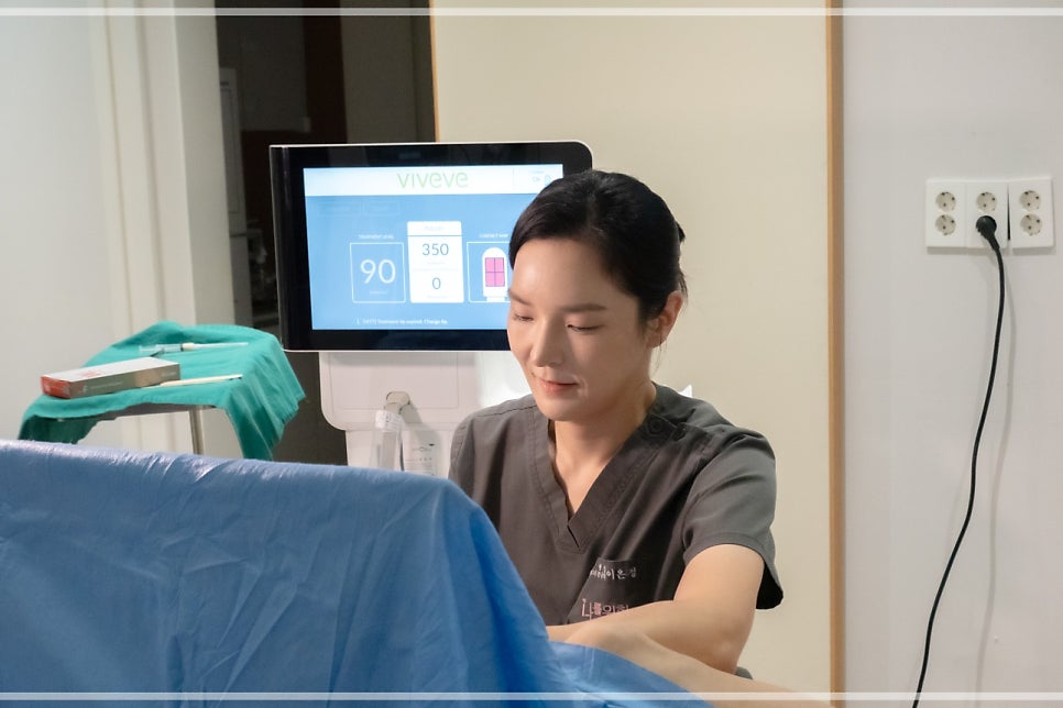 진료실 책상에서 의료진이 옆모습으로 앉아, 자궁 모형과 함께 HPV 검사 안내 스프링노트/차트를 들고 환자에