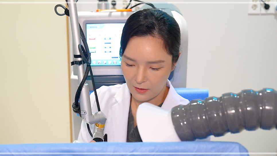 레이저 장비 화면 옆에서 흰 가운을 입은 여성 의료진의 얼굴이 클로즈업된 영상 스틸컷