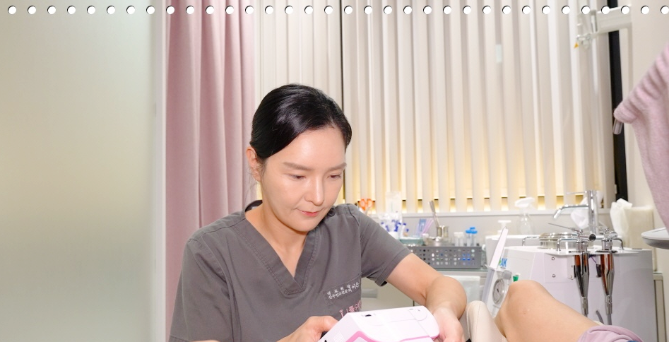 시술실에서 직원이 흰색 시술 기기를 환자의 다리 쪽에 대고 있다
