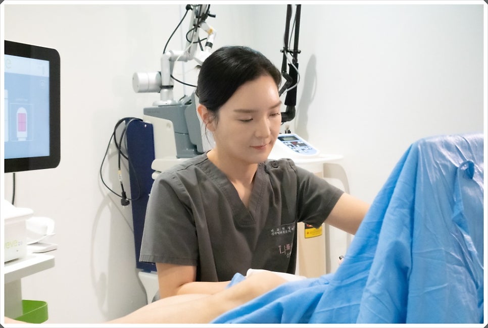 viveve로 보이는 장비 앞에서 회색 스크럽을 입은 여성 의료진이 파란 천이 덮인 환자를 향해 시술을 준비