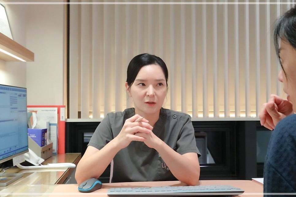 여성 직원이 데스크에서 키보드·마우스 앞에 앉아 손을 맞잡고 말하는 모습