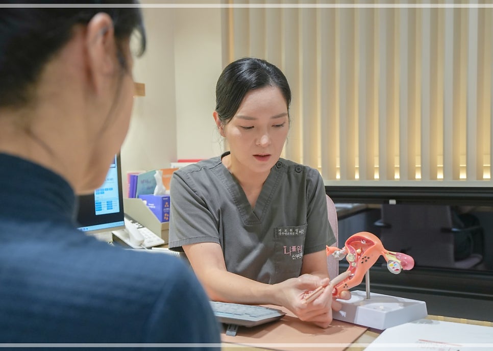 여성 직원이 두 대의 모니터(왼쪽에 골반 뼈 해부도) 앞에서 손을 맞잡고 설명하는 모습