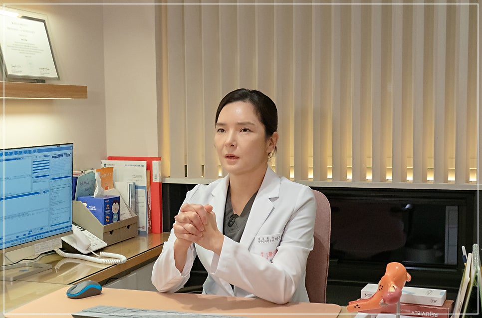 흰색 가운을 입은 의료진이 명찰을 달고 두 손을 모은 채 환자에게 설명하는 모습